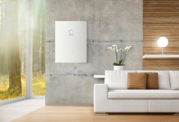 A white wall-mounted home battery (Sonnen) installed on a concrete wall in a modern living room