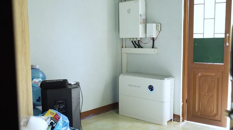 A Sigenergy home battery unit and wall-mounted inverter installed on the wall of a room next to a wooden door