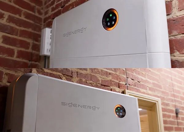 A white Sigenergy home battery unit mounted on an exposed brick wall with an illuminated status display