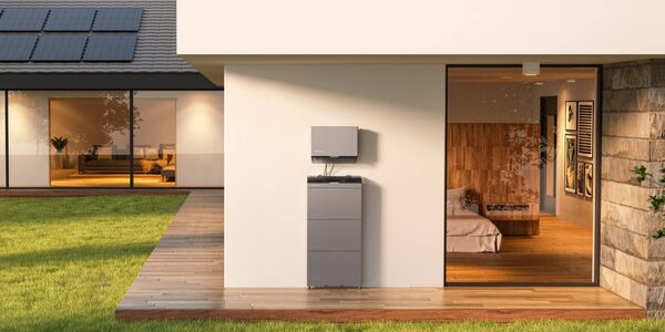 An EcoFlow home battery unit mounted on the exterior wall of a modern house with rooftop solar panels