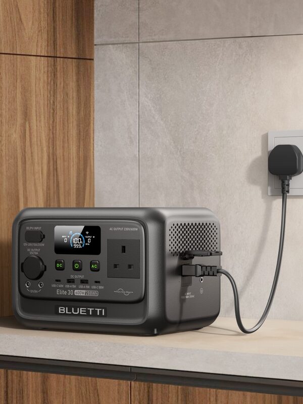 A Bluetti Elite 30 portable power station plugged into a UK wall socket on a kitchen worktop