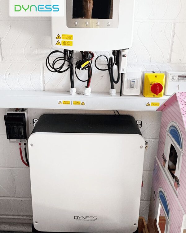 A Dyness PowerDepot H5B home battery installed on a white brick wall with an inverter, cabling and an emergency isolation switch above it