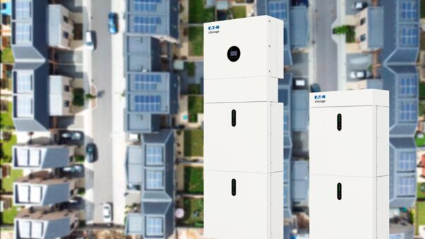 Two white Eaton xStorage hybrid home battery storage units shown against an aerial view of houses with rooftop solar panels
