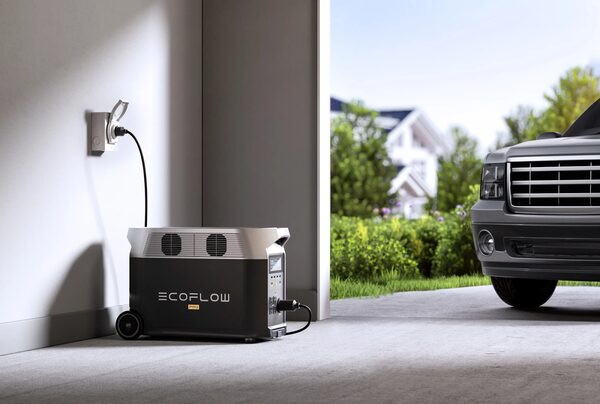 An EcoFlow portable power station charging from a wall socket in a garage next to a parked car