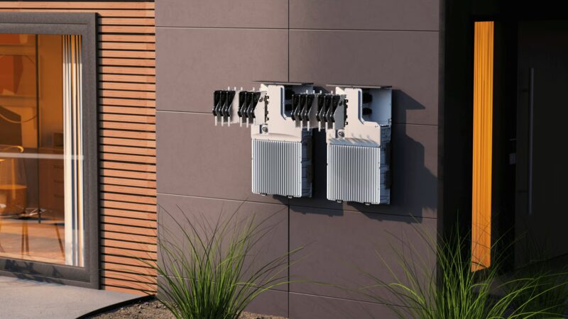 Two Enphase home battery units mounted on the exterior wall of a modern house
