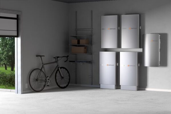 Several Enphase home battery storage units mounted on a garage wall next to a bicycle