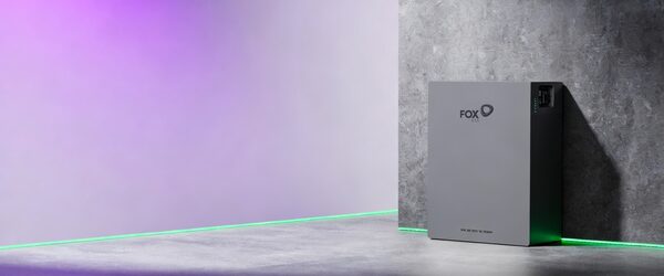 A grey Fox ESS EP5 home battery unit standing against a concrete wall in a stylised studio setting