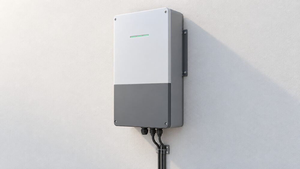 A close-up of one compact all-in-one home battery unit, a tall cabinet combining inverter and battery modules in a single enclosure, mounted on a house's outside wall with its cable glands and mounting bracket visible and nothing else in the scene.