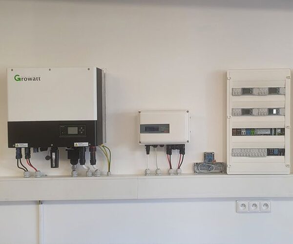 A Growatt wall-mounted battery inverter and storage system installed next to a consumer unit on an indoor wall