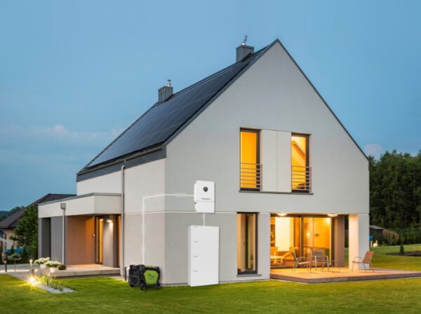 A modern house at dusk with rooftop solar panels and a Growatt home battery storage system and inverter mounted on the exterior wall