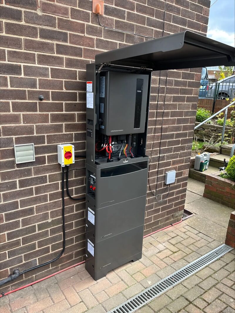A solar battery storage unit with hybrid inverter mounted on the brick exterior wall of a house