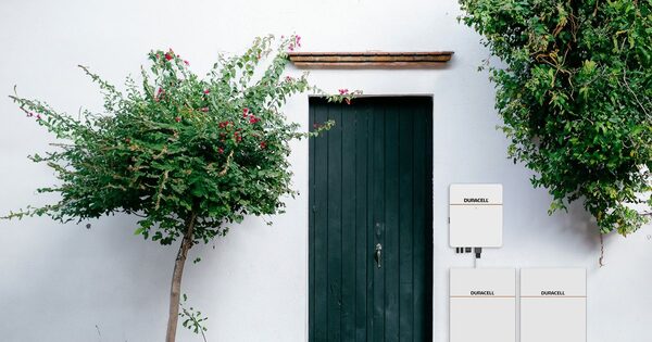 Duracell home battery units mounted on a white wall beside a green door