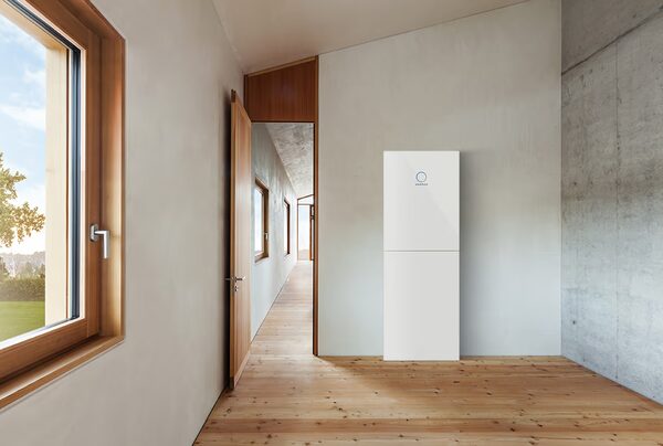 A white sonnen home battery standing against a wall in a bright modern hallway with wooden floors