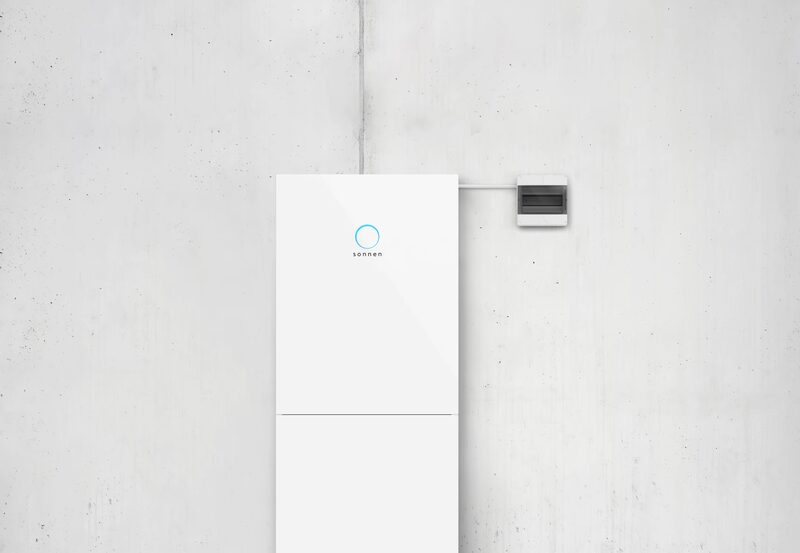 A white sonnen home battery unit mounted on a plain concrete wall next to a small meter box