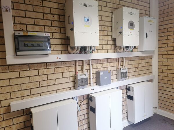 Sunsynk inverters and battery storage units installed on a brick wall with a consumer unit and cabling