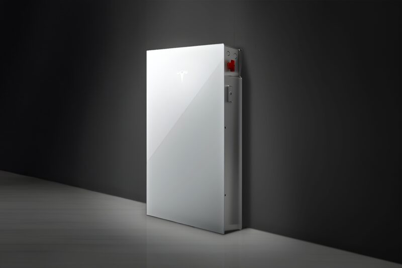 A white Tesla Powerwall home battery mounted against a dark wall