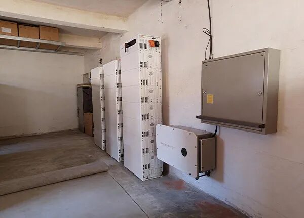 A Sigenergy home battery stack and inverter installed on the wall of a garage next to a grey distribution board