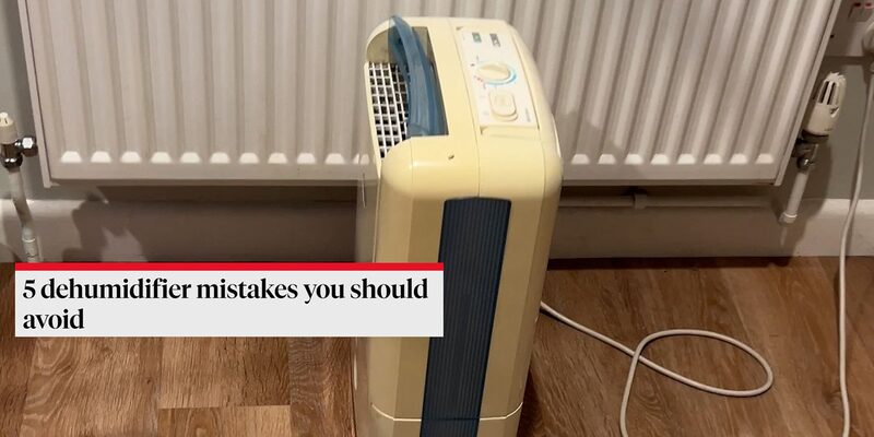 A cream dehumidifier plugged in on a wooden floor in front of a radiator, with a text overlay reading '5 dehumidifier mistakes you should avoid'