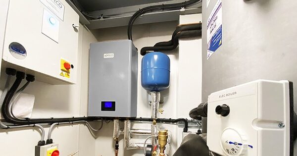 An Adveco electric boiler installed in a plant room with an expansion vessel, pipework and an 'ELEC BOILER' control box