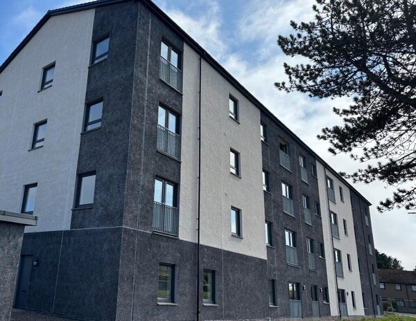 A multi-storey block of flats with newly rendered grey and white external wall insulation