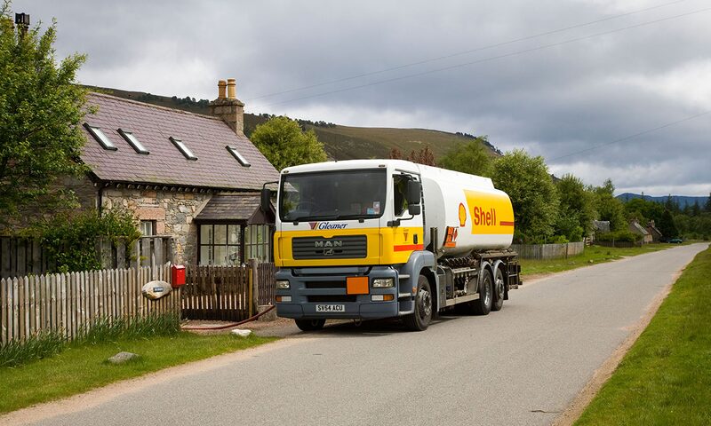A Shell heating oil tanker lorry delivering fuel outside a stone cottage in the countryside