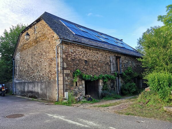 Solar panels mounted on the slate roof of an old stone barn