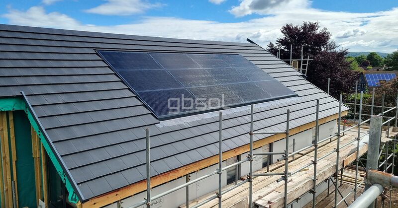 An in-roof integrated solar panel array on the slate roof of a new-build house surrounded by scaffolding