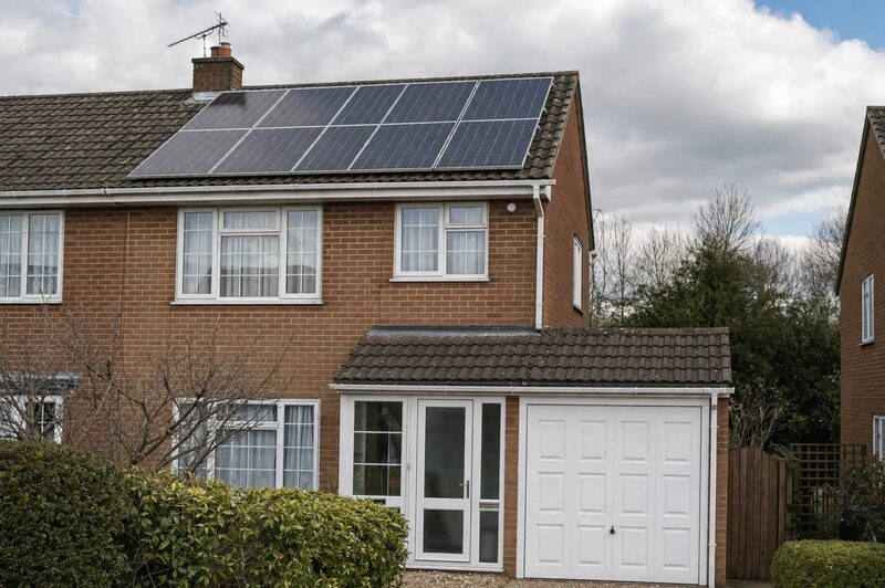 A brick semi-detached UK house with solar panels installed on its tiled roof