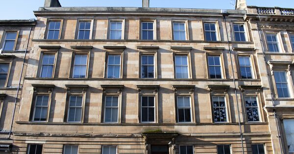 A traditional sandstone tenement building facade with sash windows in a Scottish city