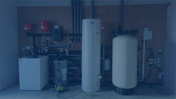 A ground source heat pump installation with cylinders, buffer vessel and pipework in a plant room