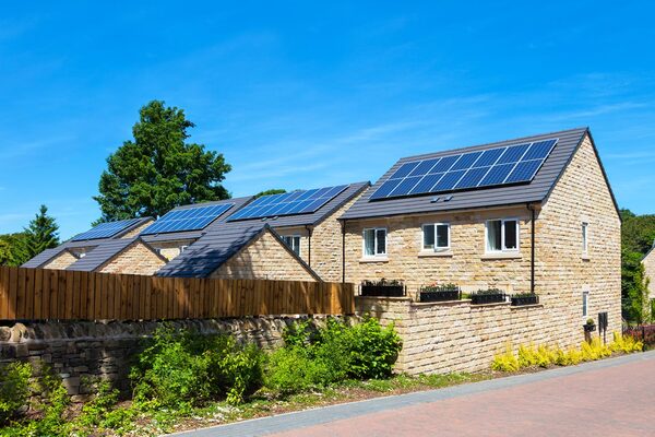 Stone-built houses with solar panels on their roofs under a blue sky
