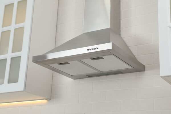A stainless steel cooker hood extractor fan installed on a white brick kitchen wall