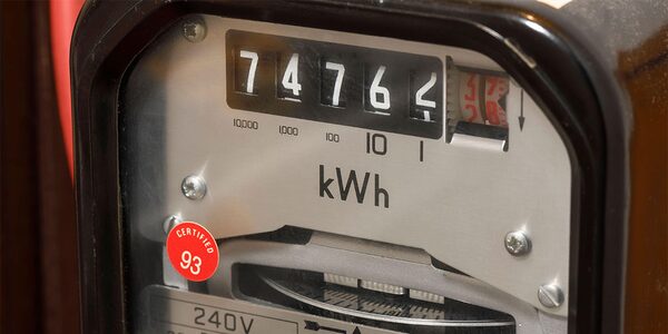 A close-up of a mechanical dial electricity meter displaying a digital-style readout of 74764 kWh