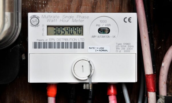 A multirate single-phase electricity meter with digital reading mounted on a wooden wall with cables