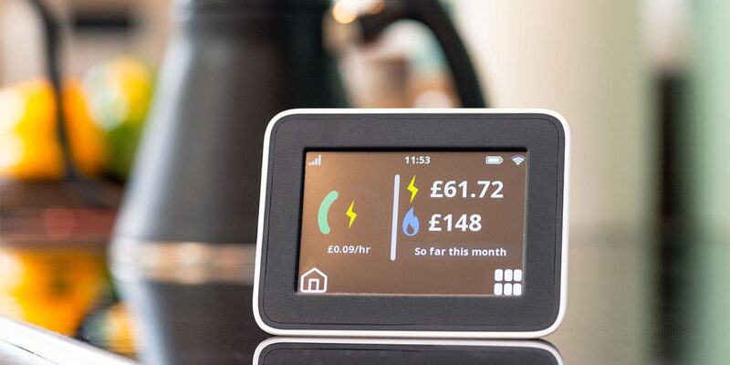 A smart meter in-home display on a kitchen counter showing electricity and gas costs so far this month