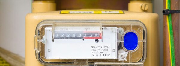 A close-up of a beige domestic gas meter with a mechanical dial register reading 02200 cubic metres