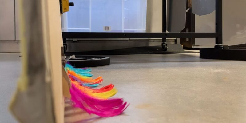 A colourful feather draught excluder strip fitted along the bottom of a door in a test setup