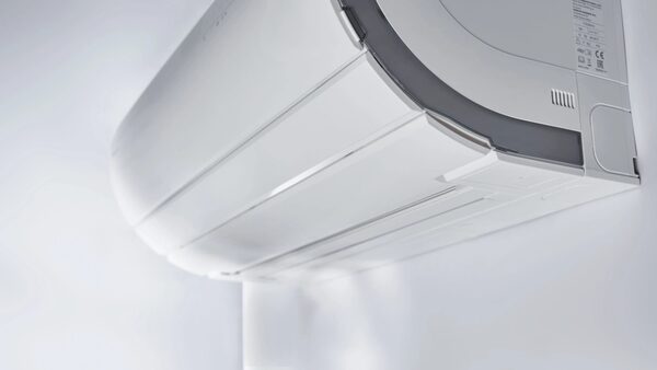 A close-up of a white Daikin wall-mounted air conditioning indoor unit on a white wall