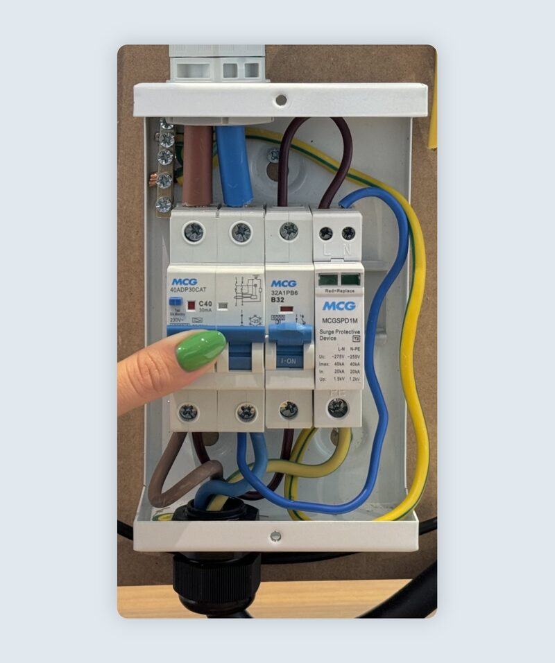 A finger switching on an MCG RCBO and MCB breakers inside a consumer unit with wiring