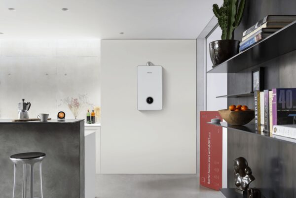 A white wall-mounted combi boiler installed in a modern kitchen, with a red BOXT promotional banner leaning nearby
