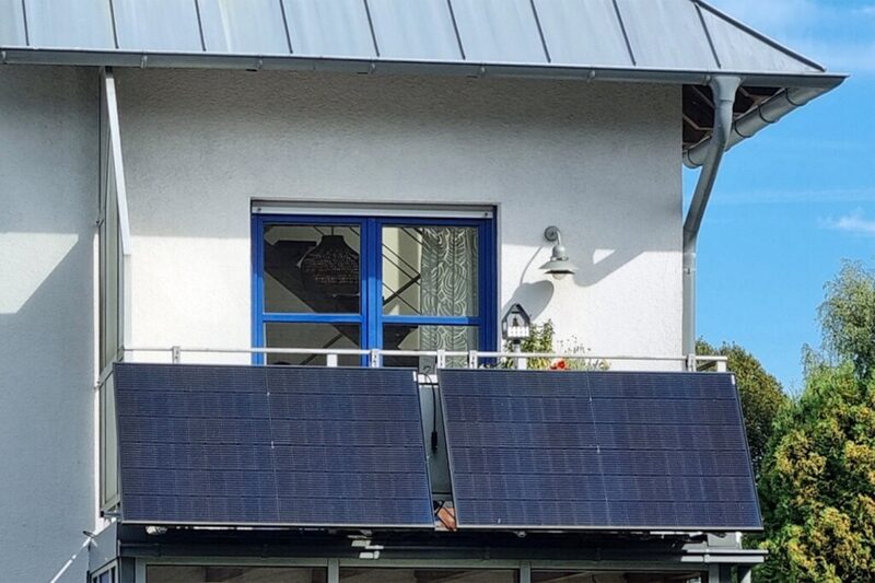 Two plug-in solar panels mounted on a house balcony railing
