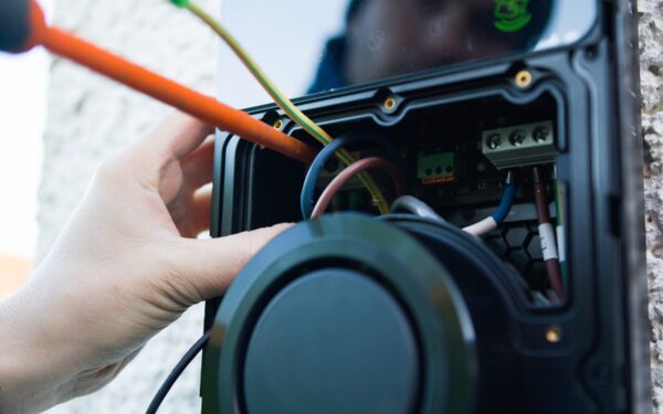 An electrician wiring the internal terminals of a wall-mounted EV charge point during installation