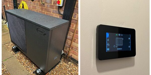 A Grant air source heat pump unit outside a brick house next to a wall-mounted smart heating controller
