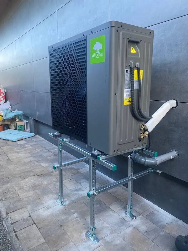 A Mycond air source heat pump unit installed on a metal stand outside a house wall