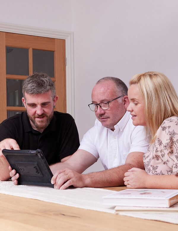 An installer showing a tablet to a couple at a table in a home