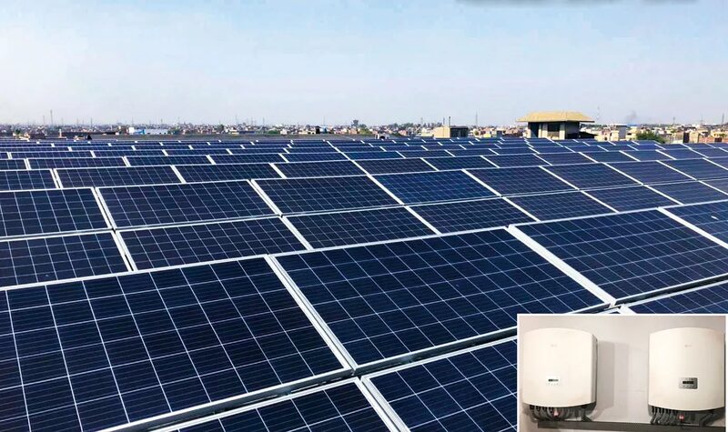 A large rooftop solar panel installation with an inset photo of two wall-mounted solar inverters
