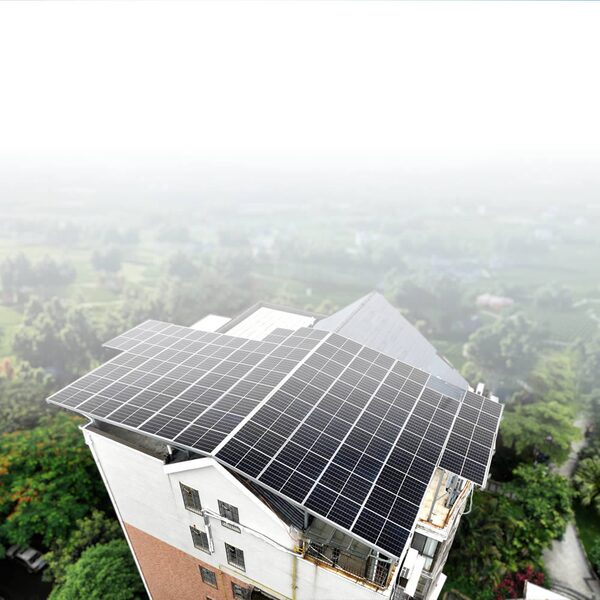 A rooftop covered in solar panels on a residential building overlooking a hazy green landscape