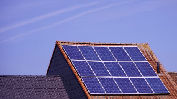 Solar panels installed on the tiled roof of a house against a blue sky