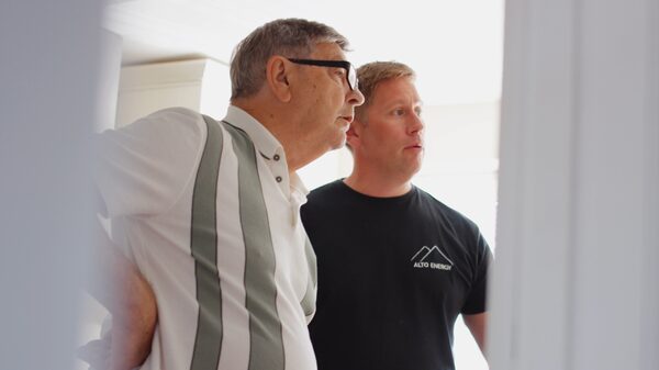 An Alto Energy engineer in a branded black t-shirt talking with a householder indoors