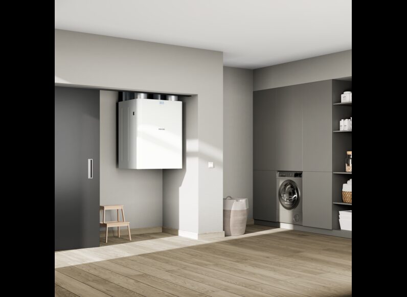 A white Stiebel Eltron VRC-W 600 ventilation unit mounted high on a wall in a modern utility room with grey fitted cupboards and a washing machine